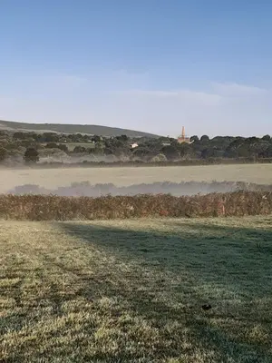 a field with fog in the distance and a field with a field at The Shepherd Hut in Carleen