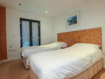 two beds in a bedroom with white sheets at Apartment 3 in Newquay