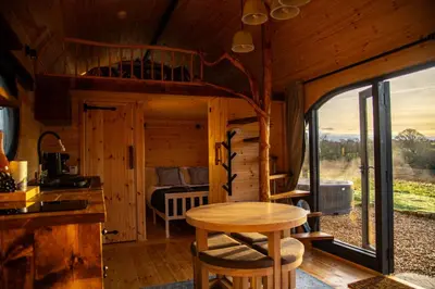 a kitchen and dining room of a log cabin with a table at The Palm at OLJU Lodges in Ponsanooth
