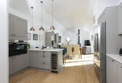 a kitchen with white cabinets and a dining room at Whitewood in Camborne