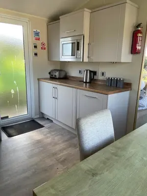 a small kitchen with white cabinets and a microwave at Rubys Retreat - 6 Berth Caravan in Newquay, Cornwall in Newquay