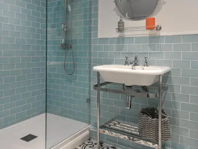a blue tiled bathroom with a sink and a shower at Crew Quarters in Fowey