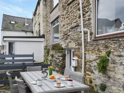 a table and chairs on a patio with a building at Crew Quarters in Fowey
