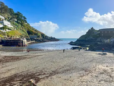 a beach with people on the sand and the ocean at Harbour Studio in Polperro