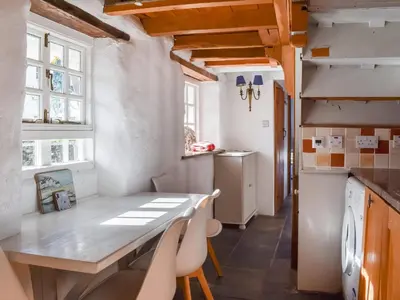 a kitchen with a table and chairs in a room at Harbour Studio in Polperro