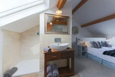 a bathroom with a sink and a bed and a mirror at Little Bream - pretty cosy cottage, sea views, walk to the beach in Mawnan Smith