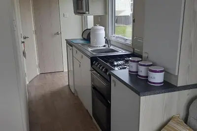 a small kitchen with a stove and a sink at PerranporthCaravan 2bedroom Tv GasFire in Perranporth