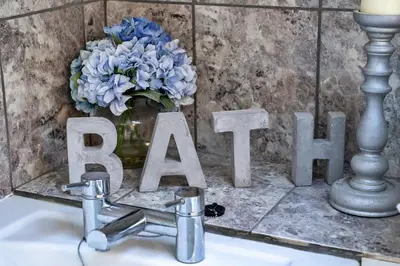 a sink with a vase of blue flowers and a sign at Finest Retreats - Trennal Barn in Germoe