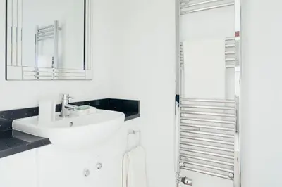 a white bathroom with a sink and a mirror at 3 The Elms in St Ives