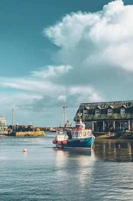 a boat sitting in the water in front of a building at Apartment Jetty Cottage by Interhome in Mevagissey