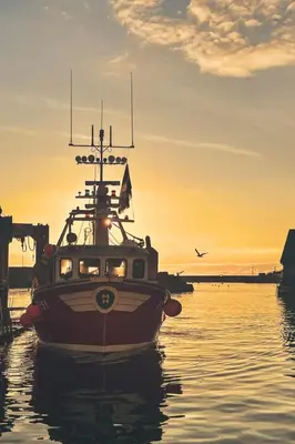 a boat in the water with a sunset in the background at Apartment Jetty Cottage by Interhome in Mevagissey