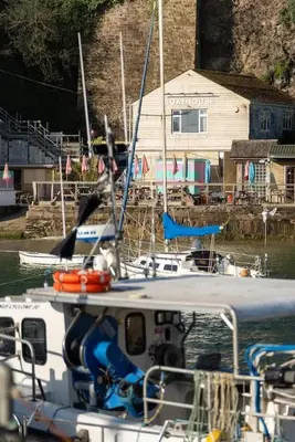 a boat is docked in the water near a house at Spacious Flat Sea Views & Private Parking Fistral in Newquay