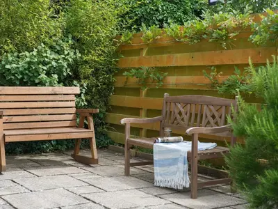 two wooden benches sitting in front of a wall at Curlew in Wadebridge