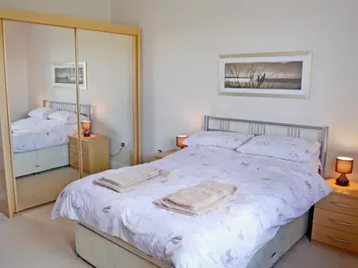 a bedroom with a large bed and a mirror at Swallows in Mount Hawke