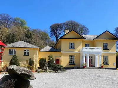 a large yellow house with a large driveway at Rosecraddoc Manor - Stable in Saint Cleer