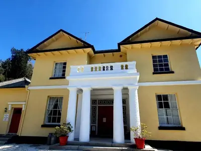a yellow building with white pillars in front of it at Rosecraddoc Manor - Stable in Saint Cleer