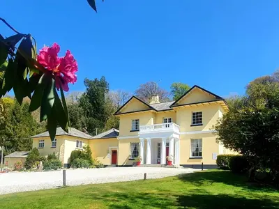 a large yellow house with a flower in the yard at Rosecraddoc Manor - Riverbank in Saint Cleer
