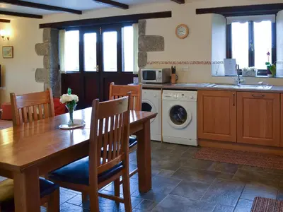 a kitchen with a table and a washing machine at Eglos Derry Farm Cottage - E4597 in Cury