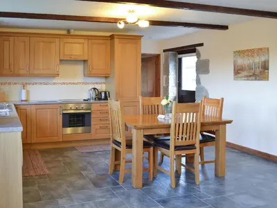 a kitchen with a wooden table and chairs at Eglos Derry Farm Cottage - E4597 in Cury