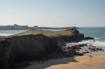 a beach with a rocky shoreline and the ocean at Apartment Sea Views 5 mins Walk to Fistral in Newquay