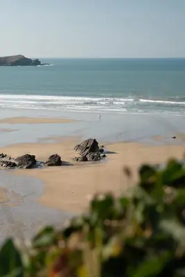 a beach with rocks in the sand and the ocean at Apartment Sea Views 5 mins Walk to Fistral in Newquay
