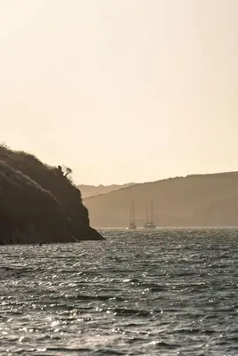 two boats floating on the water near a cliff at Apartment Sea Views 5 mins Walk to Fistral in Newquay