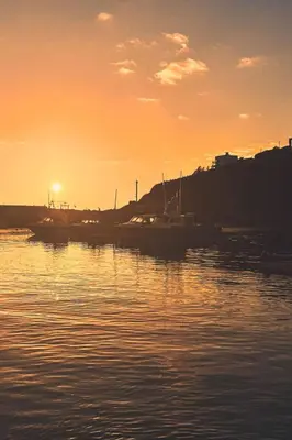 a sunset over a harbor with boats in the water at Holiday Home Piskey Cottage by Interhome in Mevagissey