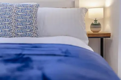a bed with a blue and white pillow and a lamp at 2 Bed in Fowey oc-r30265 in Fowey