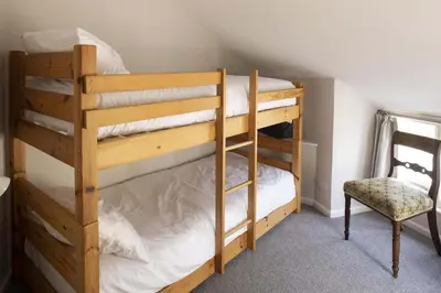 a couple of bunk beds in a room with a chair at Gorgeous Cottage Parking Short Walk to Beach in Gorran Haven
