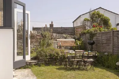 a patio with chairs and a table in a yard at Gorgeous Cottage Parking Short Walk to Beach in Gorran Haven