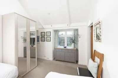 a bedroom with a mirror and a bed and a window at Samson Cottage in Saint Mawgan