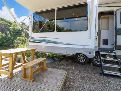 an rv with a wooden deck and a picnic table at Tickeydoo, Tor Down Quarry in Bodmin