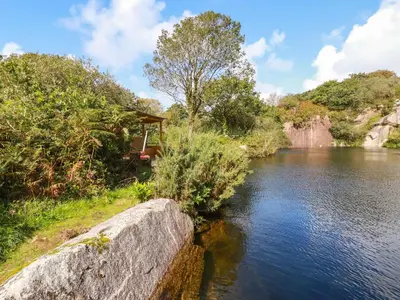a river with a stone wall next to the water at Tickeydoo, Tor Down Quarry in Bodmin