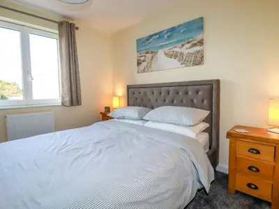 a bedroom with a large white bed with a window at Freesia in Truro