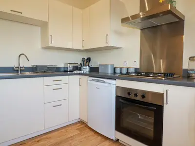 a kitchen with white cabinets and a stove top oven at Freesia in Truro