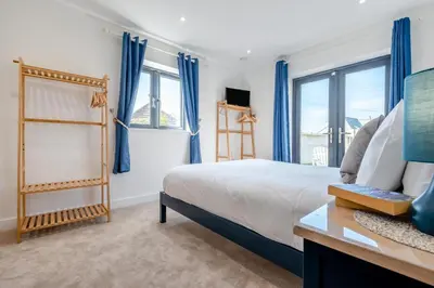 a bedroom with a bed with blue curtains and windows at 4 Bed in Porthleven oc-ch30536 in Porthleven