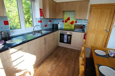 a kitchen with wooden cabinets and black counter tops at TwoPigalliie Heights in Nancekuke