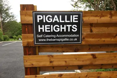 a sign on a wooden fence with a sign on it at TwoPigalliie Heights in Nancekuke