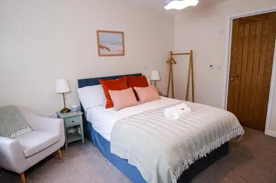 a bedroom with a bed and a chair in it at Epiphany House in Kenwyn