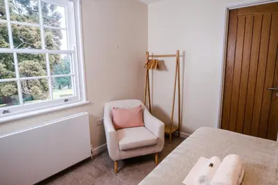 a bedroom with a chair and a bed and a window at Epiphany House in Kenwyn
