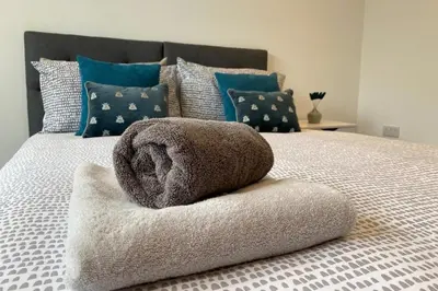 a bed with a towel on top of it at Coastal house, large garden, 4 bedrooms, 2 bathrooms, BBQ, 10 min walk to beach in Mawnan Smith