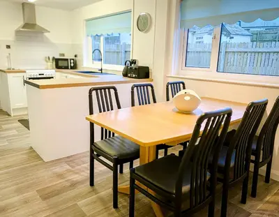 a kitchen and dining room with a wooden table and chairs at Trelawne in Bude
