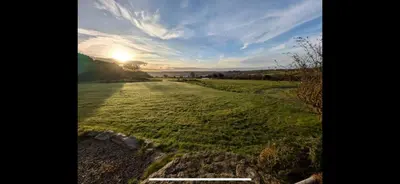 a field of grass with the sun in the sky at Seaview Barns in Budock Water