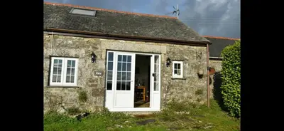 an old stone cottage with a white door at Seaview Barns in Budock Water
