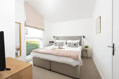a white bedroom with a bed and a window at 71 Una, Carbis Bay in Carbis Bay
