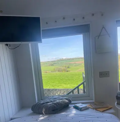 a bedroom with a window with a view of a green field at Hillview Haven in Liskeard