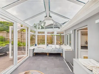 a conservatory with a bed in a room with windows at Cosy Cornish Cottage with Firepit & Parking in Newlyn East