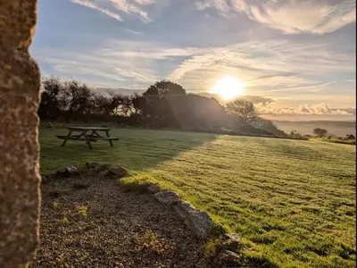 a picnic table in a field with the sunset in the background at Seaview Stable Barn in Penryn