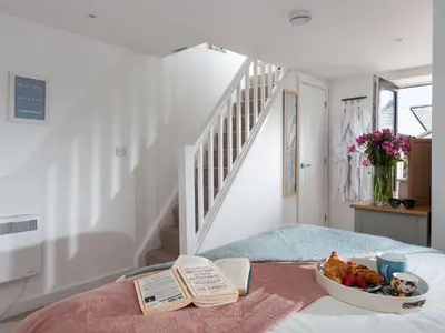 a bedroom with a bowl of fruit and books on a bed at The Loft in Porthleven