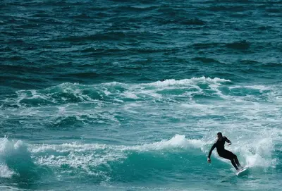 a person riding a wave on a surfboard in the ocean at Cinq 5 Zinc in Fistral, Newquay in Newquay